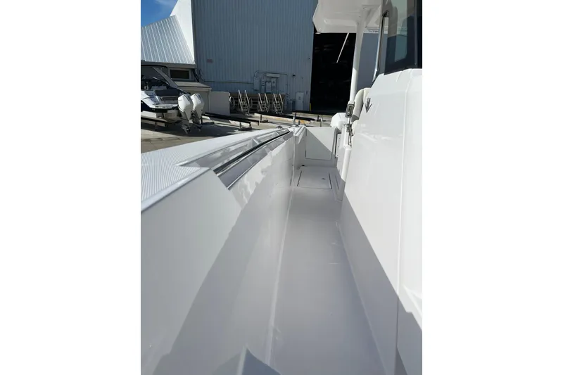 Slide: The Image of 2023 Bertram 28 CC boat deck, sleek white design, docked near a warehouse. - 4