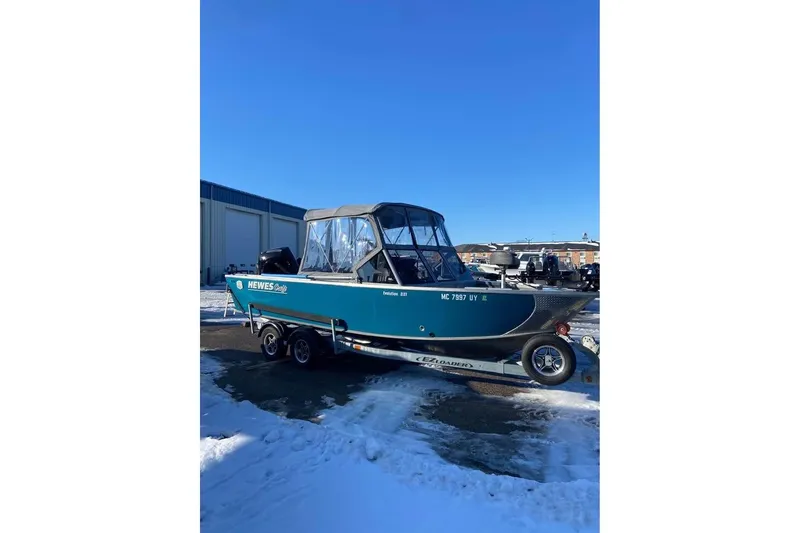 The Image of 2024 Hewescraft 221 Evolution boat on trailer, parked in snowy outdoor setting. - 0