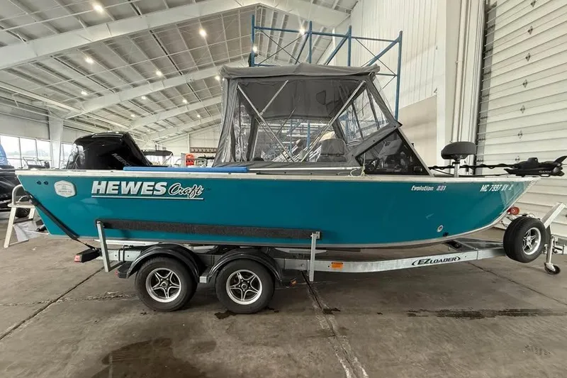 Slide: The Image of 2024 Hewescraft 221 Evolution boat on trailer in indoor showroom. - 2