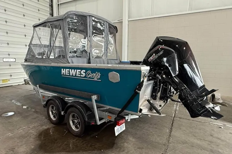 Slide: The Image of 2024 Hewescraft 221 Evolution boat with outboard motor in a garage setting. - 4