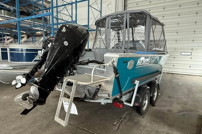 Slide: The Image of 2024 Hewescraft 221 Evolution boat with outboard motor in a warehouse setting. - 5