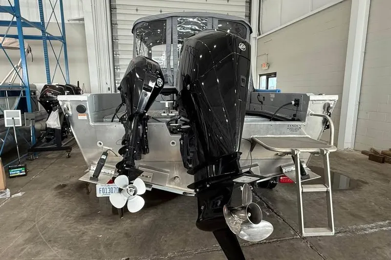 Slide: The Image of 2024 Hewescraft 221 Evolution boat with dual outboard motors in a garage. - 6