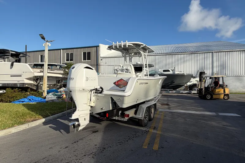 Slide: The Image of 2018 Sportsman Heritage 241 Center Console boat on trailer, parked near industrial building. - 5