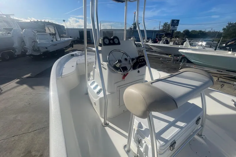 Slide: The Image of 2016 NauticStar 2110 Sport boat interior with steering console and seating, docked outdoors. - 4