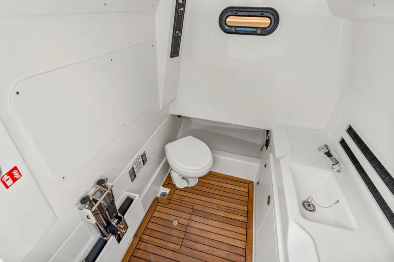 Slide: The Image of Interior of a boat cabin with a toilet, sink, and wooden floor. - 24