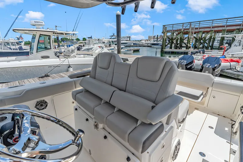 Slide: The Image of The image shows the cockpit of a Boston Whaler 330 Outrage with gray seats in a marina. - 16