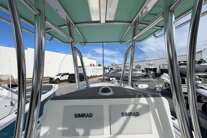 Slide: The Image of 2023 Contender 24 Sport boat with Simrad electronics, parked in a marina under clear skies. - 15