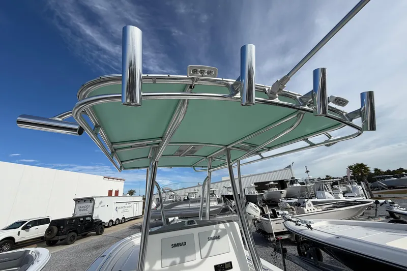Slide: The Image of 2023 Contender 24 Sport boat with T-top and rod holders, parked at a marina. - 9