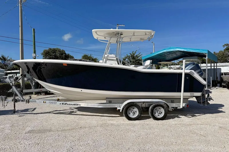Slide: The Image of 2012 Tidewater 230 CC Adventure boat on trailer, parked outdoors under clear blue sky. - 4