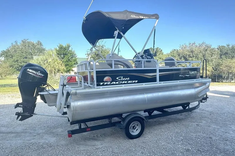 Slide: The Image of 2022 Sun Tracker Bass Buggy 16 XL pontoon boat with Mercury outboard motor on trailer. - 2