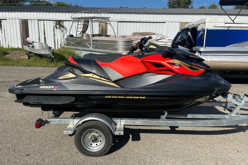 The Image of 2019 Sea-Doo RXP-X 300 jet ski on trailer, black and red design. - 0