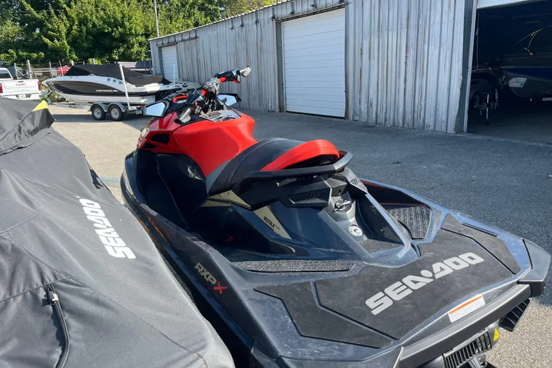 Slide: The Image of 2019 Sea-Doo RXP-X 300 jet ski parked near boats and a garage. - 2