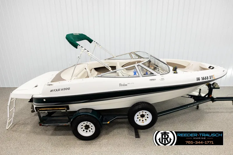 Slide: The Image of 2003 Four Winns 180 Freedom I/O boat on trailer, white with green accents. - 1