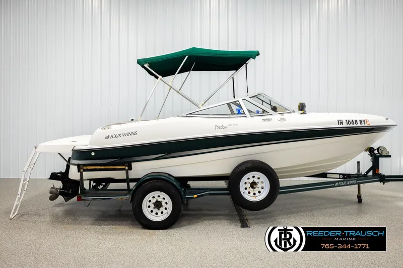 Slide: The Image of 2003 Four Winns 180 Freedom I/O boat on trailer with green canopy in showroom. - 4