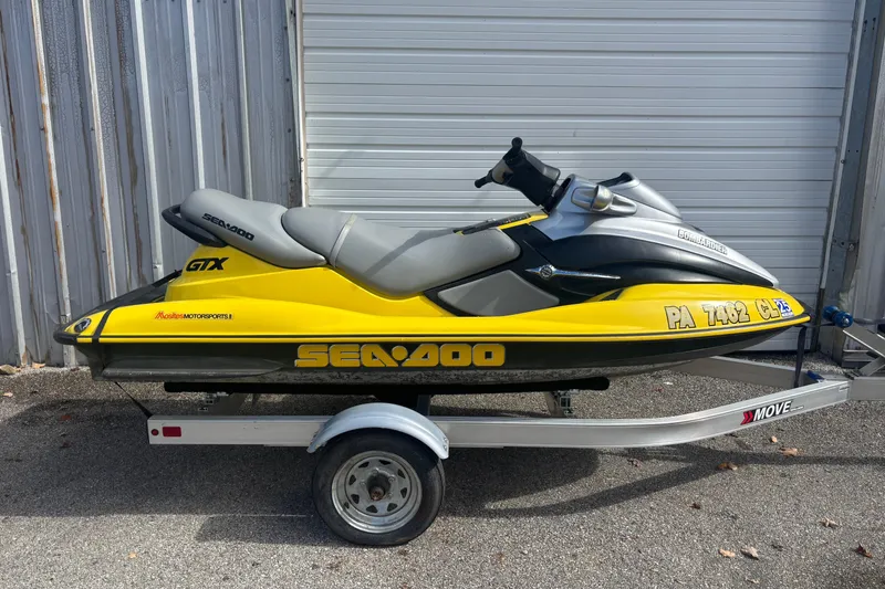 The Image of 2002 Sea-Doo GTX jet ski on trailer, yellow and black, parked outdoors. - 0