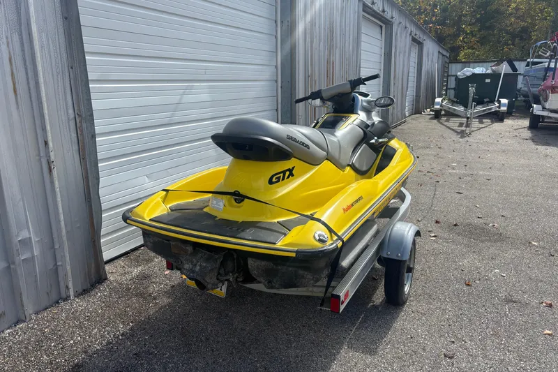 Slide: The Image of 2002 Sea-Doo GTX jet ski on trailer, parked near storage units. - 3