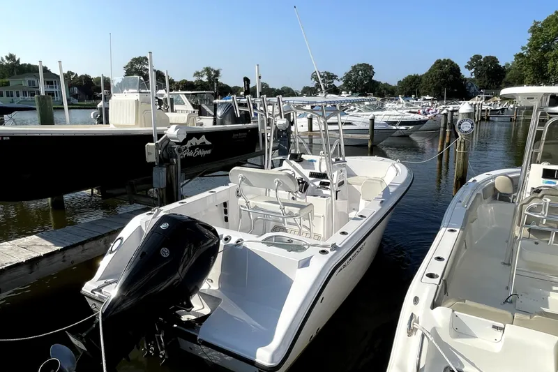 Slide: The Image of 2024 Aquasport 2200 Center Console boat docked at a marina. - 2