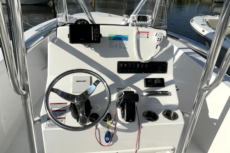 Slide: The Image of 2024 Aquasport 2200 Center Console boat dashboard with steering wheel and controls. - 4