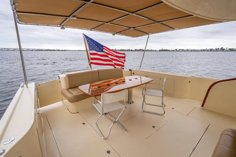 Slide: The Image of 2018 Palm Beach Motor Yachts PB55 deck with seating, table, and American flag. - 12