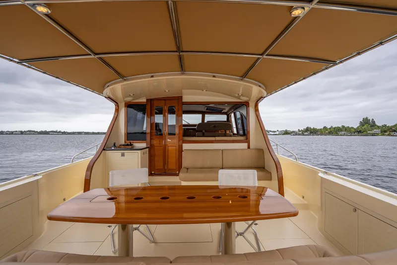 Slide: The Image of 2018 Palm Beach Motor Yachts PB55 interior with elegant seating and wooden table on open water. - 16