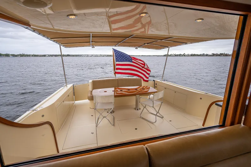 Slide: The Image of 2018 Palm Beach Motor Yachts PB55 aft deck with American flag and seating area. - 17