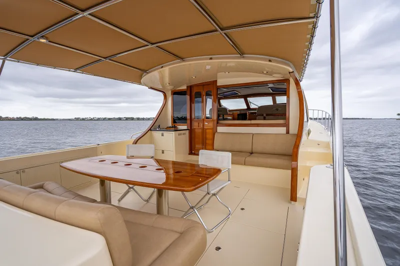 Slide: The Image of 2018 Palm Beach Motor Yachts PB55 interior with elegant seating and wooden table on open water. - 1