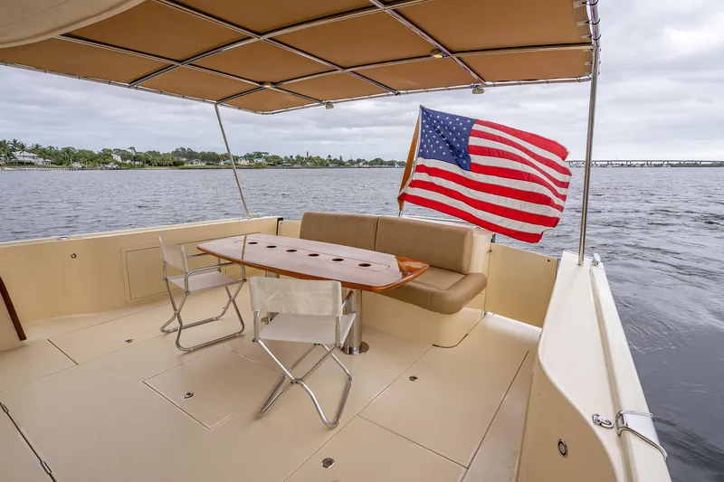 Slide: The Image of 2018 Palm Beach Motor Yachts PB55 deck with seating, table, and American flag. - 13