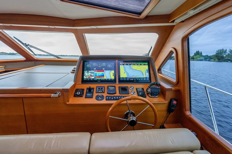 Slide: The Image of 2018 Palm Beach Motor Yachts PB55 helm with navigation screens and wooden steering wheel. - 32