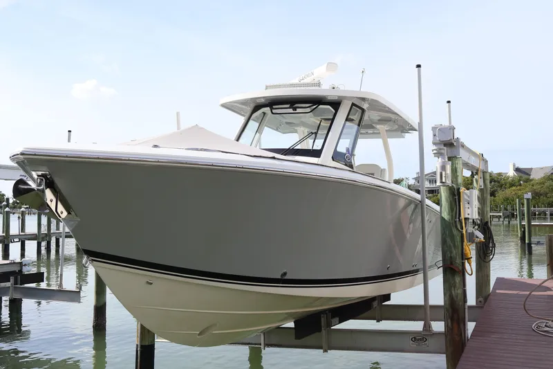 Slide: The Image of 2021 Pursuit S 328 Sport boat docked on a lift by the water. - 11