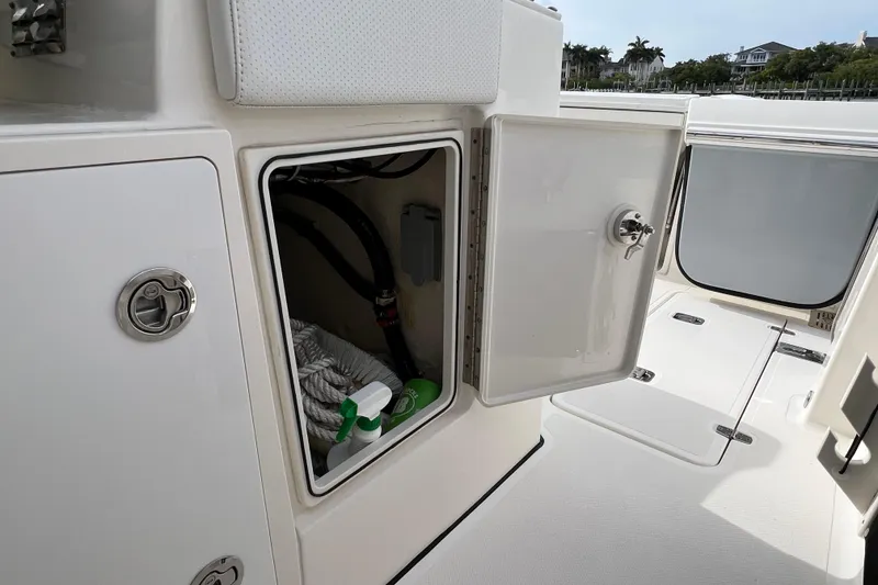Slide: The Image of 2021 Pursuit S 328 Sport boat storage compartment with cleaning supplies and ropes. - 25