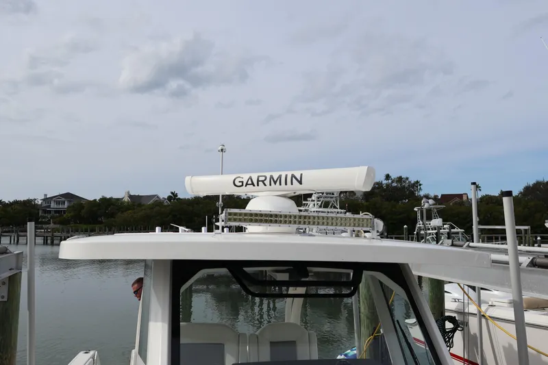 Slide: The Image of 2021 Pursuit S 328 Sport boat with Garmin radar, docked near waterfront homes. - 54