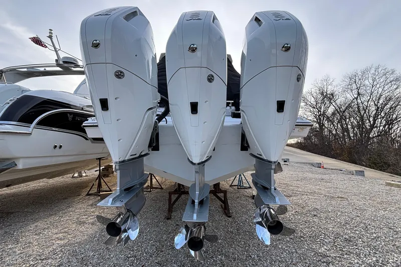 Slide: The Image of 2026 Monterey 385 Super Express with triple outboard engines on gravel lot. - 2