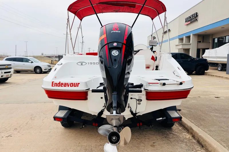 Slide: The Image of Tahoe 1950 boat, 2021 model, with red canopy and "Endeavour" text, parked outside dealership. - 7