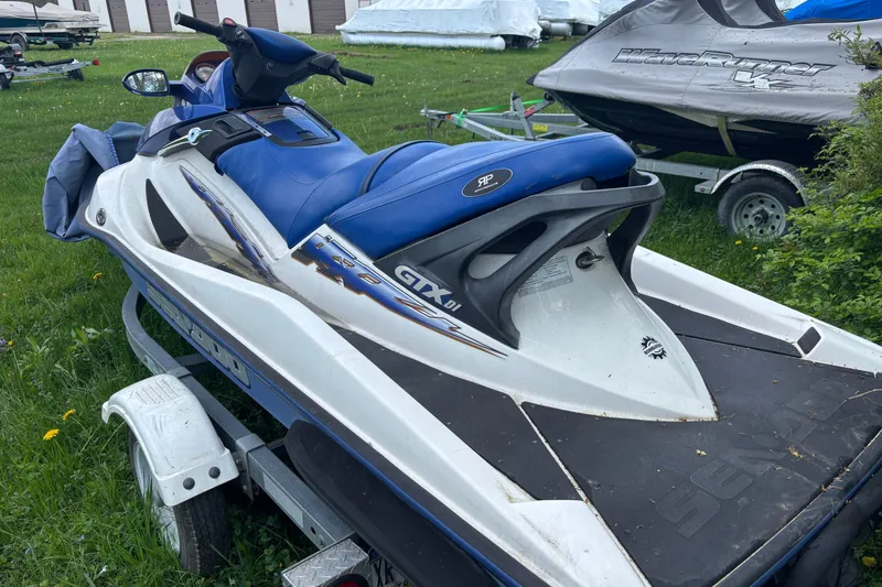Slide: The Image of 2002 Sea-Doo GTX DI jet ski on trailer, parked on grass. - 2
