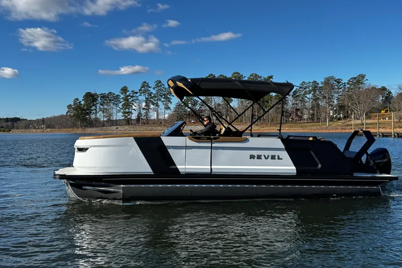 Slide: The Image of 2026 Revel RS25 pontoon boat cruising on a lake under a clear blue sky. - 10