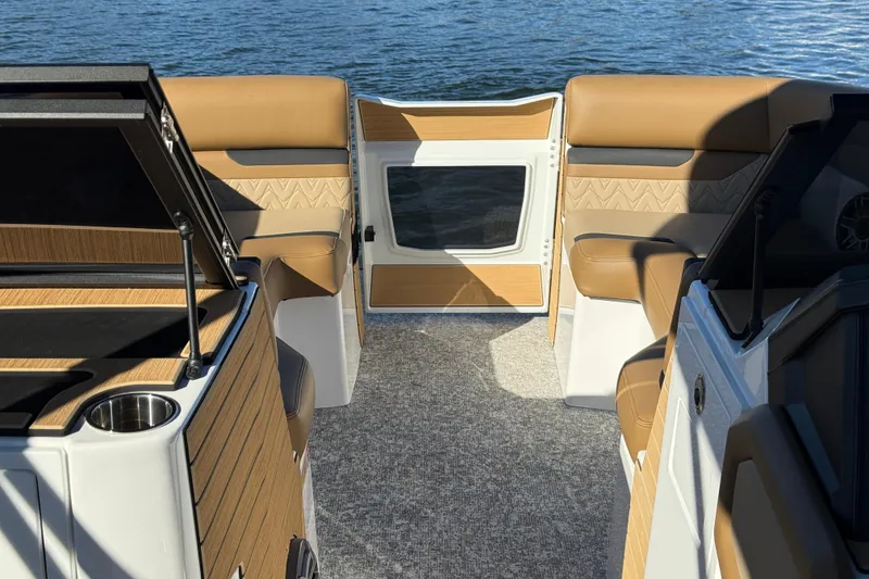 Slide: The Image of 2026 Revel RS25 boat interior with tan seating and wood accents, overlooking water. - 14