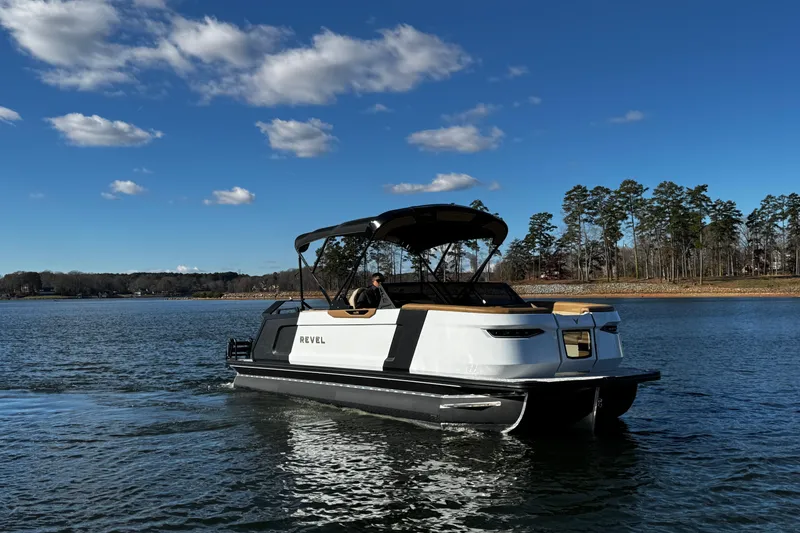Slide: The Image of 2026 Revel RS25 boat cruising on a serene lake under a clear blue sky. - 2