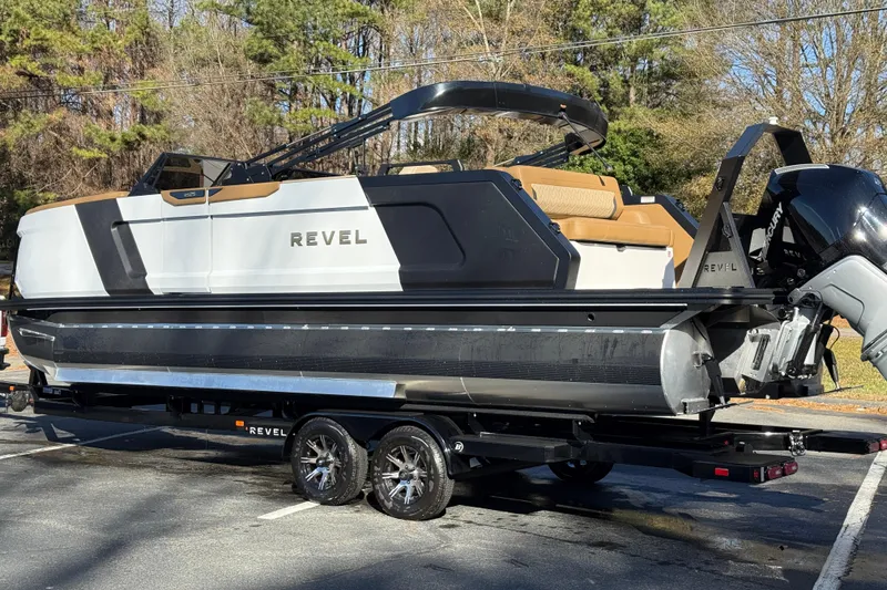 Slide: The Image of 2026 Revel RS25 pontoon boat on trailer, parked outdoors with trees in background. - 25