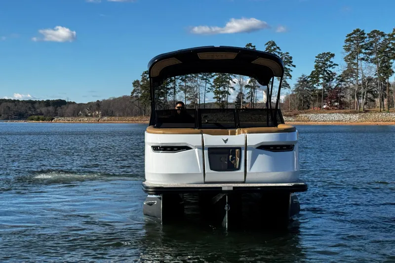 Slide: The Image of 2026 Revel RS25 pontoon boat on a serene lake with trees in the background. - 6