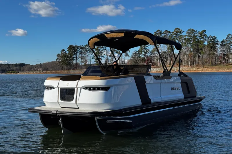 Slide: The Image of 2026 Revel RS25 pontoon boat on a serene lake with clear blue skies. - 8