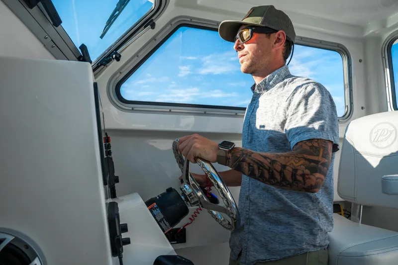 Slide: The Image of Man steering 2026 Parker 227 Explorer boat, wearing sunglasses and cap. - 9