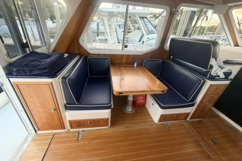 Slide: The Image of Spacious seating area on 2006 True North 38 boat with blue cushions and wooden tables. - 4