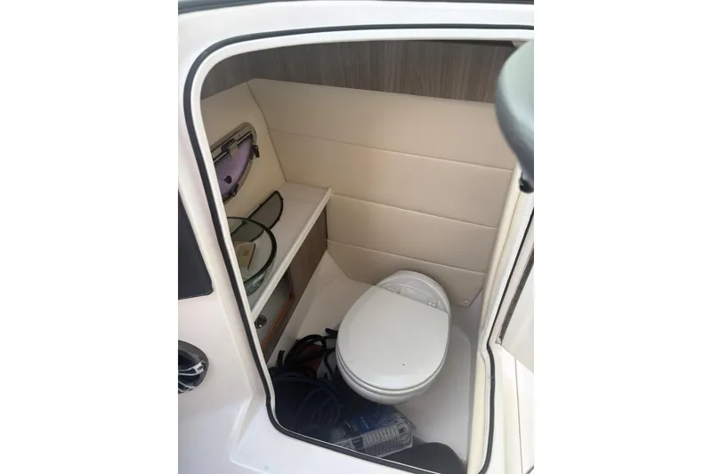 Slide: The Image of 2022 Regal 29 OBX boat interior with compact bathroom and storage shelf. - 17