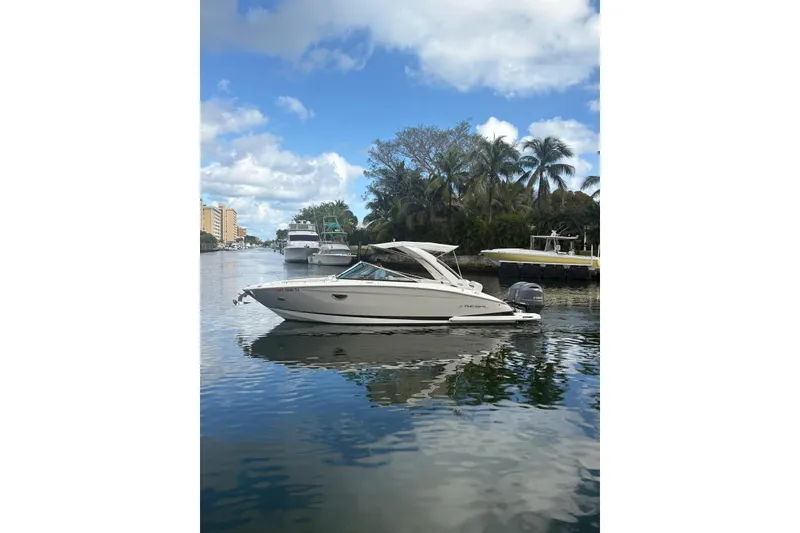 Slide: The Image of 2022 Regal 29 OBX boat on a calm waterway with palm trees and blue sky. - 2