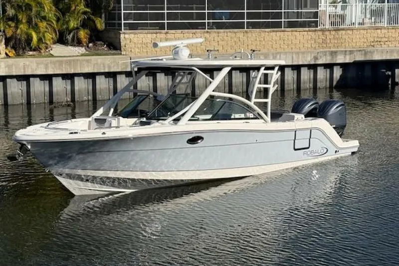 Slide: The Image of 2021 Robalo R317 Dual Console boat on calm water near a dock. - 23
