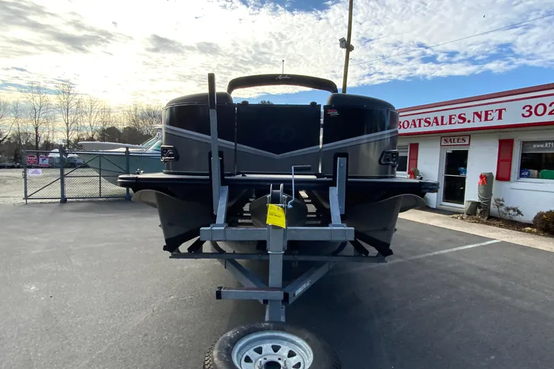 Slide: The Image of 2021 Avalon LSZ Quad Lounger boat on trailer at dealership, under cloudy sky. - 4