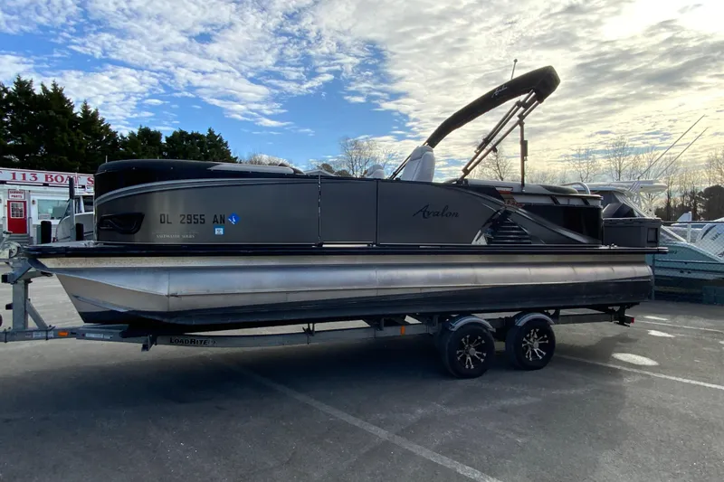 Slide: The Image of 2021 Avalon LSZ Quad Lounger 24' pontoon boat on trailer under cloudy sky. - 6