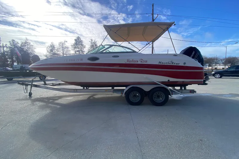 Slide: The Image of 2007 NauticStar 230DC Sport Deck boat on trailer, red and white design, outdoor setting. - 6
