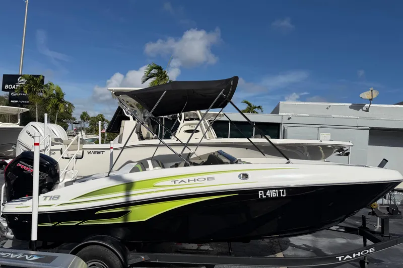 The Image of 2023 Tahoe T18 boat with canopy on trailer, displayed outdoors under blue sky. - 1