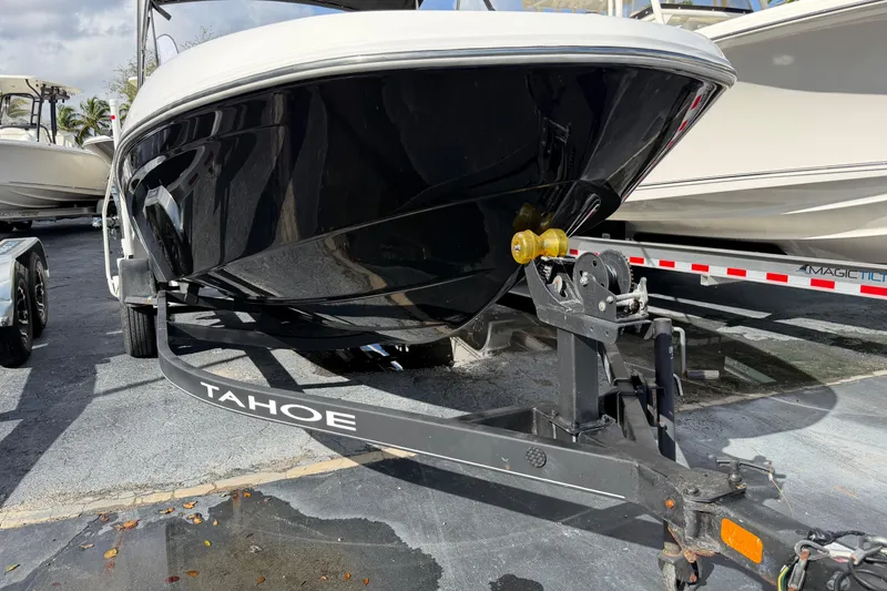 Slide: The Image of 2023 Tahoe T18 boat on trailer, black hull, parked outdoors. - 29